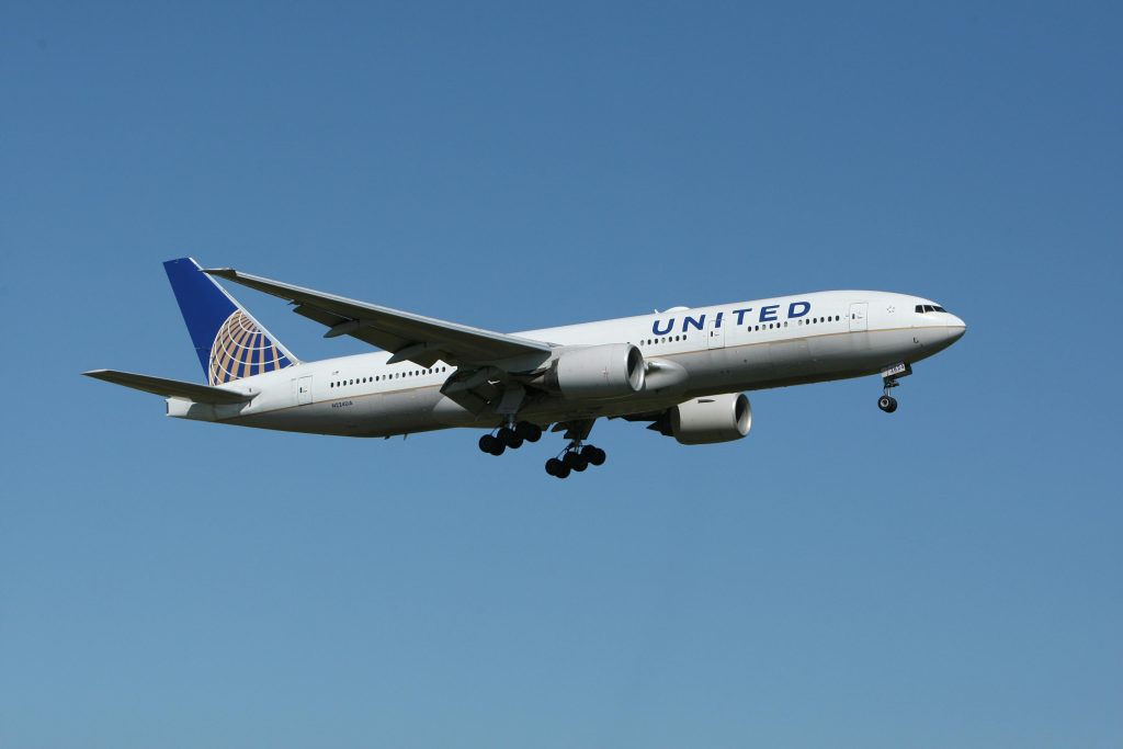 A United airliner flying against a clear blue sky, showcasing air travel.