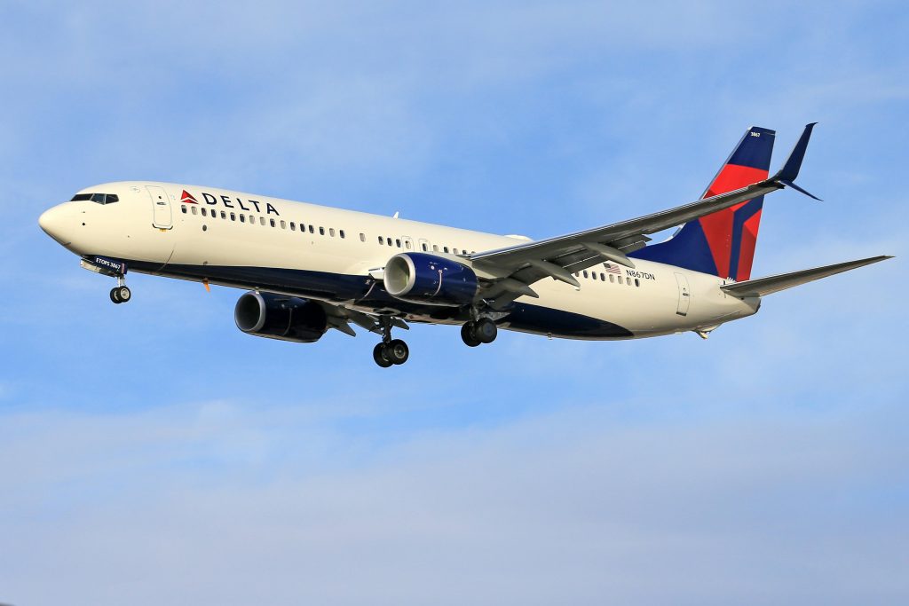 Delta airline passenger plane flying in clear blue sky. Ideal for travel and transportation themes.